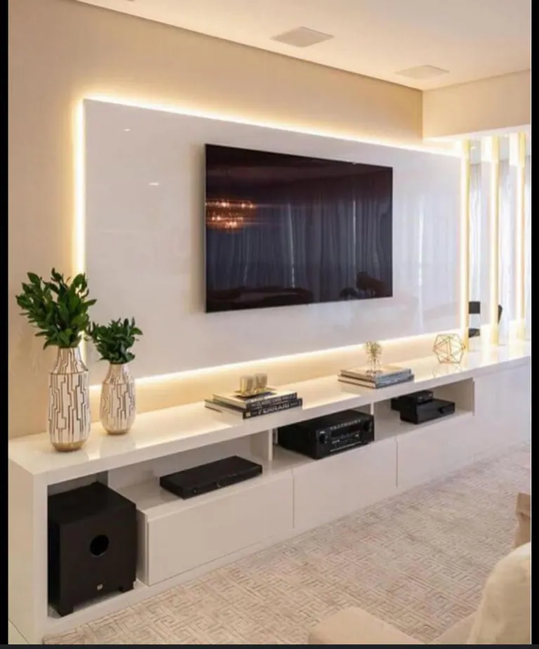 Painel de televisão branco com iluminação indireta e móvel baixo integrado